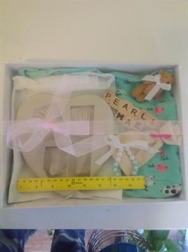 Gift set for a newborn featuring wooden letters, a bear, decorative paper, and measuring tape.