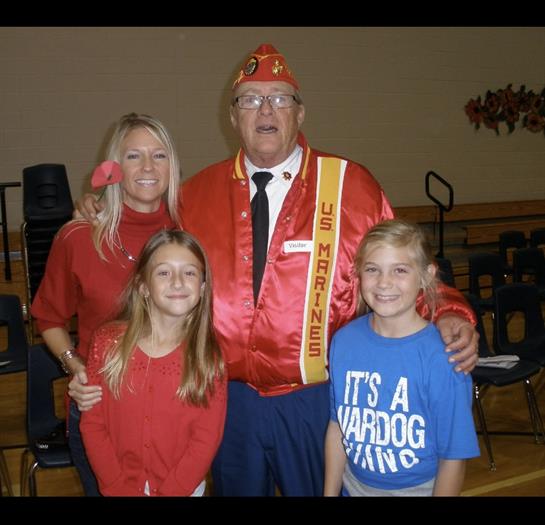 A man with two girls and a woman in a red uniform