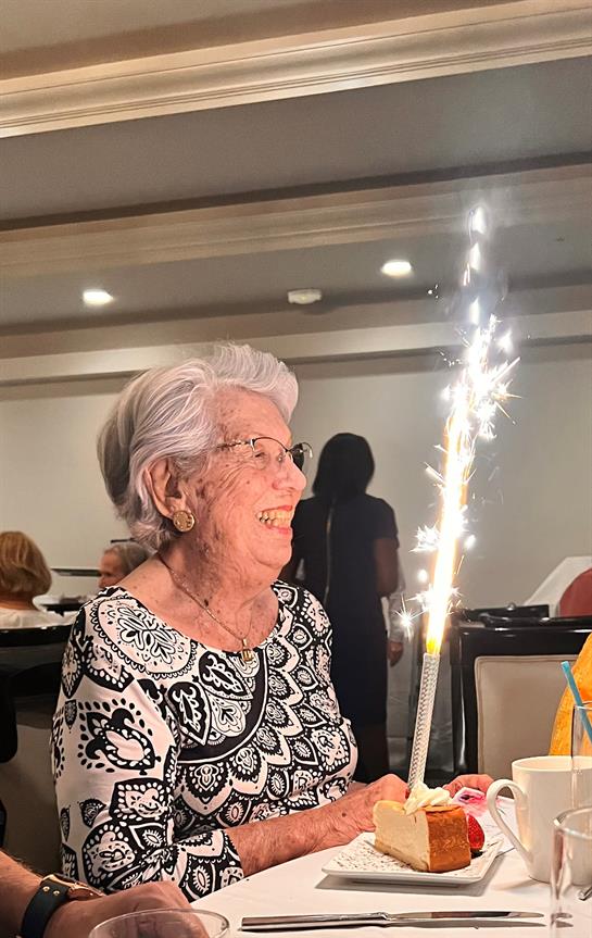 A cheerful elderly woman enjoys a celebratory moment at a festive gathering with sparklers.
