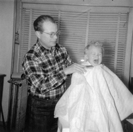 A man holding a baby's haircut