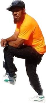 Person wearing an orange shirt and black pants kneels on one knee, looking around in a sunny area.