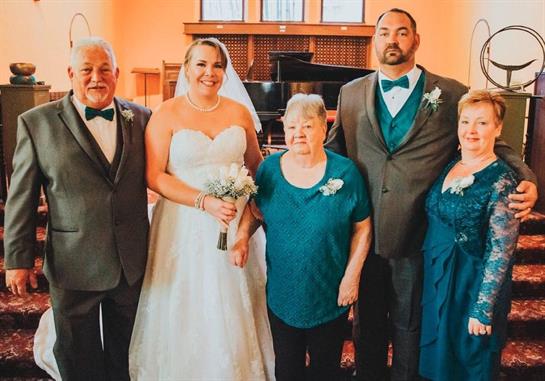 A joyful moment captures a bride with her family, all elegantly dressed, smiling together.