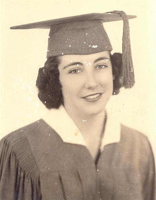 Young woman in cap and gown smiles, radiating achievement and pride.