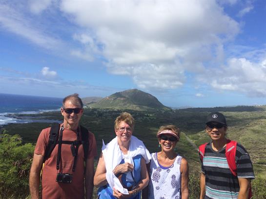 Friends pose together on a mountain trail with a breathtaking landscape in the background.