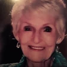 A joyful elderly woman smiles brightly, showcasing her lively spirit, in a dimly lit environment.