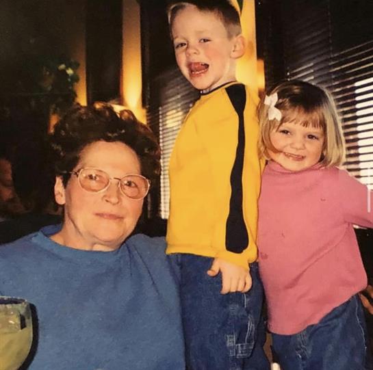 Grandmother enjoys quality time with her two cheerful grandchildren at a restaurant during dinner.