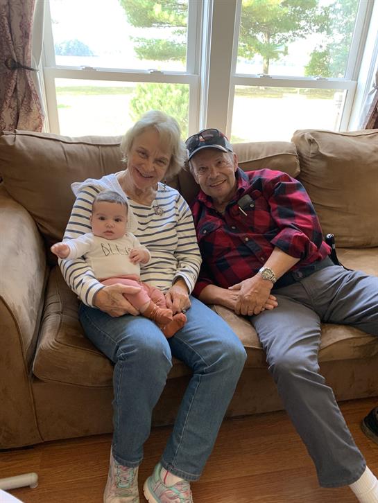 A man and woman sitting on a couch with a baby