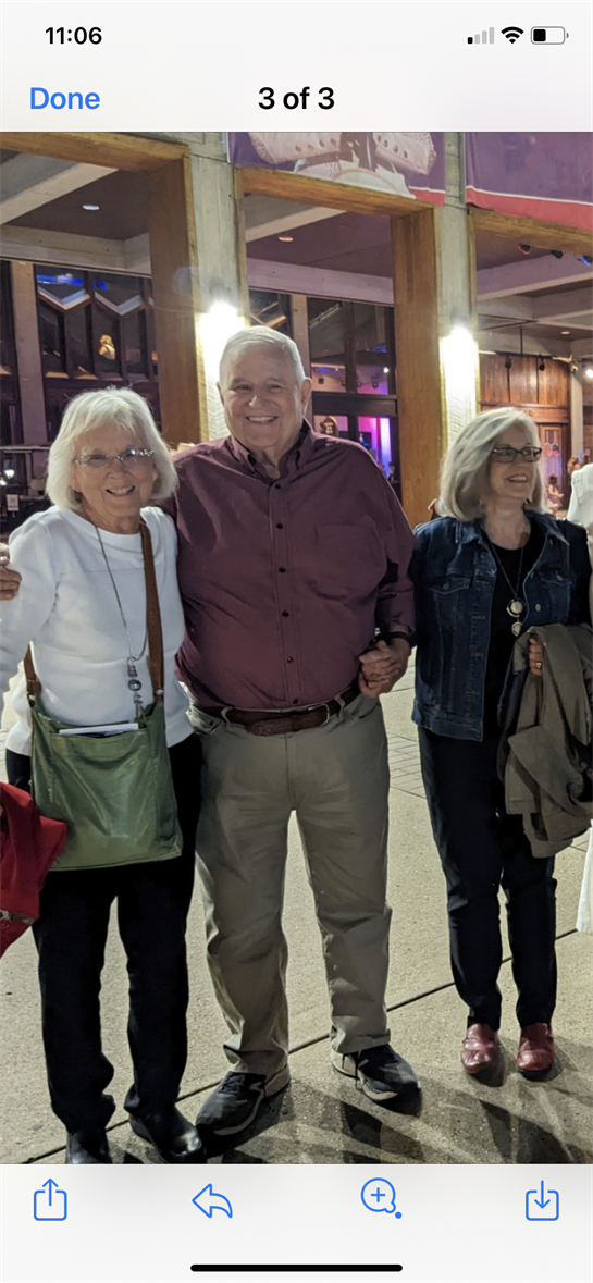 Three friends pose together outside a venue, smiling and celebrating their evening together.