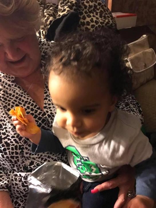 Elderly woman enjoys quality time with a young child while sharing snacks in a warm setting.