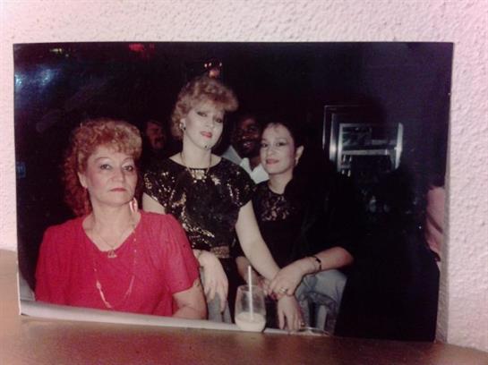 Three women socializing and having fun at a local bar under dim lighting.