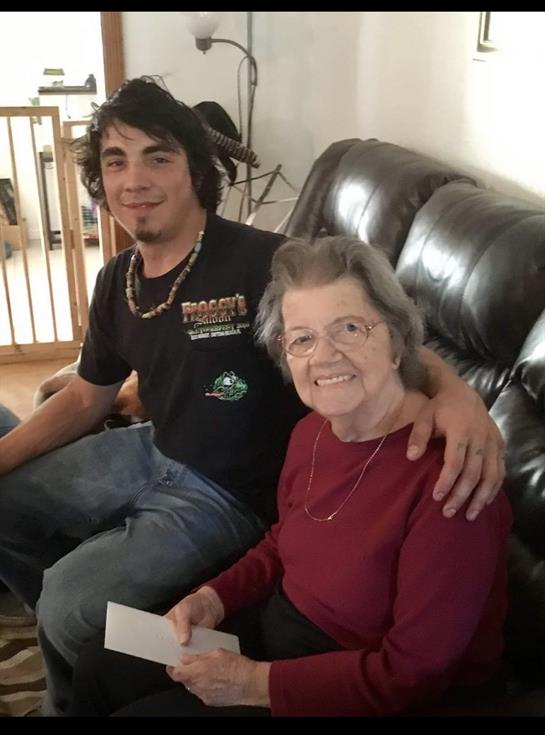 A young man and an older woman share a joyful moment together while sitting on a couch at home.