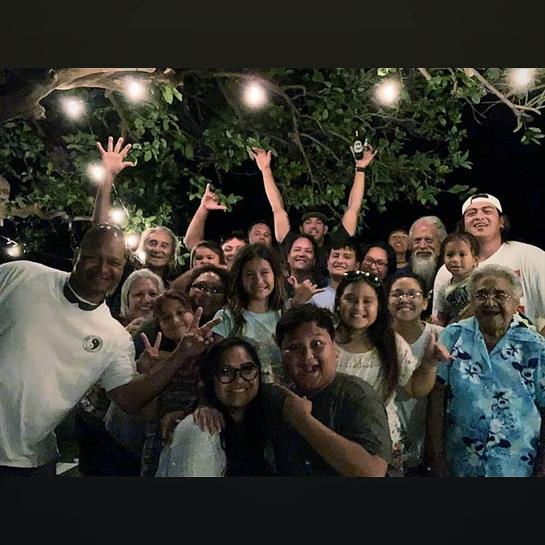 A joyful family celebrates together outdoors at night, surrounded by festive lights and laughter.