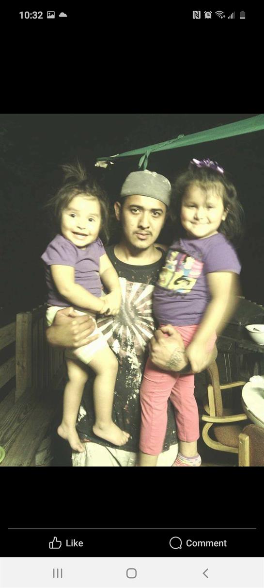 A father embraces his cheerful daughters during a joyful night outdoors, surrounded by nature.