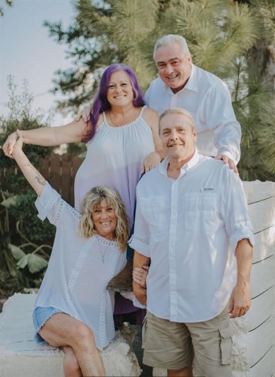Four family members enjoy a cheerful moment outdoors, engaging with one another in bright clothing.