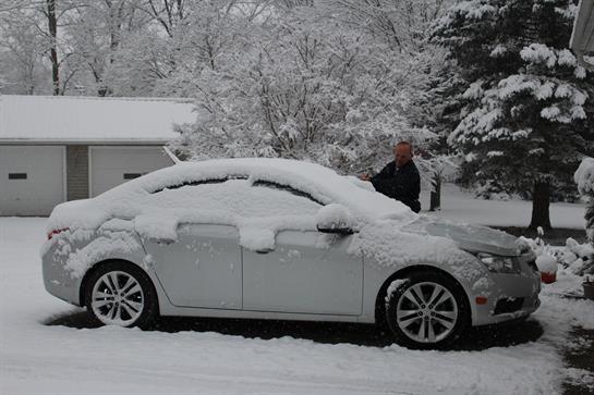 A car is buried under snow in a quiet residential area, showcasing winter's heavy snowfall.