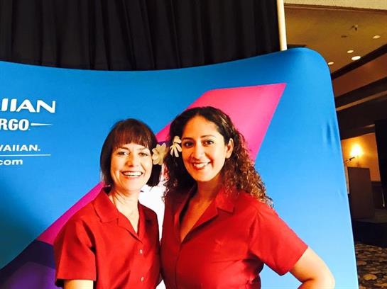 Two employees pose together at a corporate gathering, proudly wearing red uniforms and smiles.