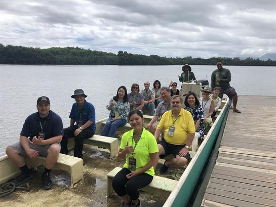 Tourists relax on a boat while exploring a river in a lush tropical environment.