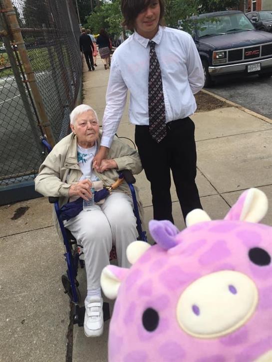 A man standing next to an old woman in a wheelchair