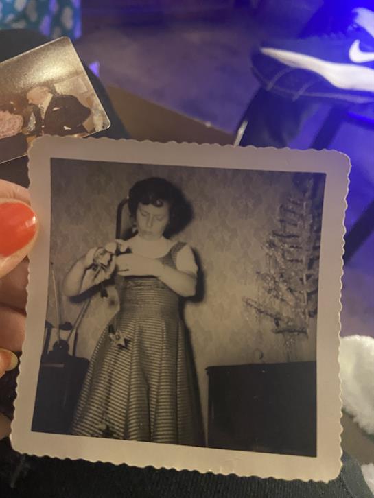 A hand holding a photo of a woman