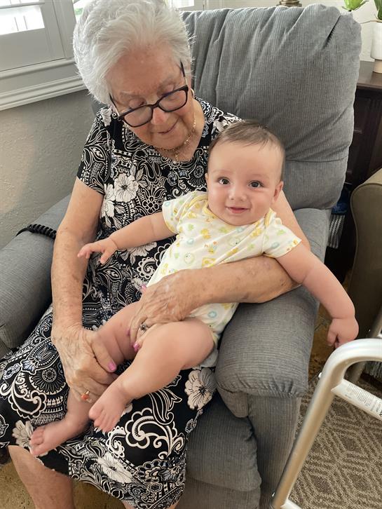 An elderly woman enjoys quality time with a smiling baby in a relaxed living room setting.