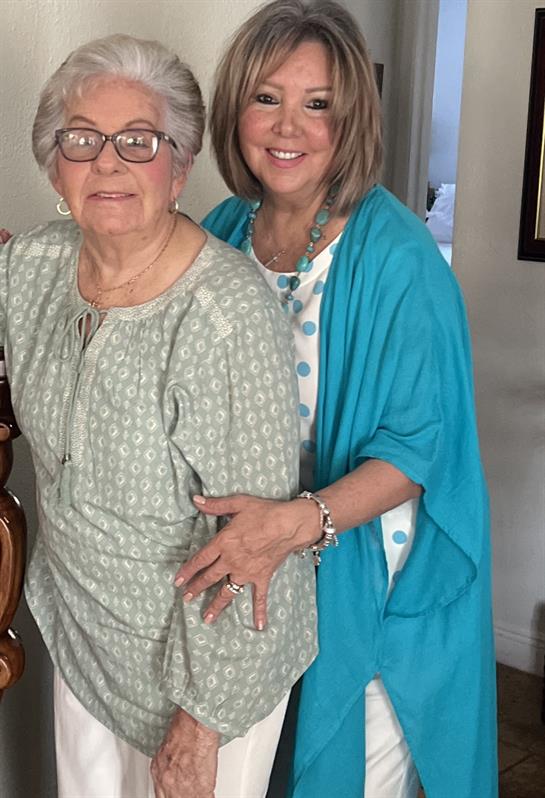 Two women embrace happily in a sunny living room, enjoying each other's company and warmth.