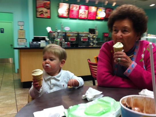 A young child and a grandmother share joyful moments while savoring ice cream cones.