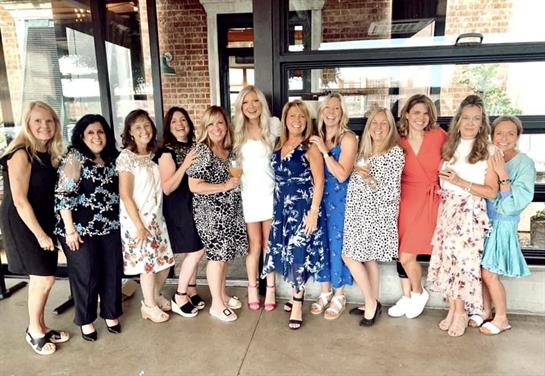 A lively group of women dressed in colorful outfits enjoy a cheerful celebration at a venue.