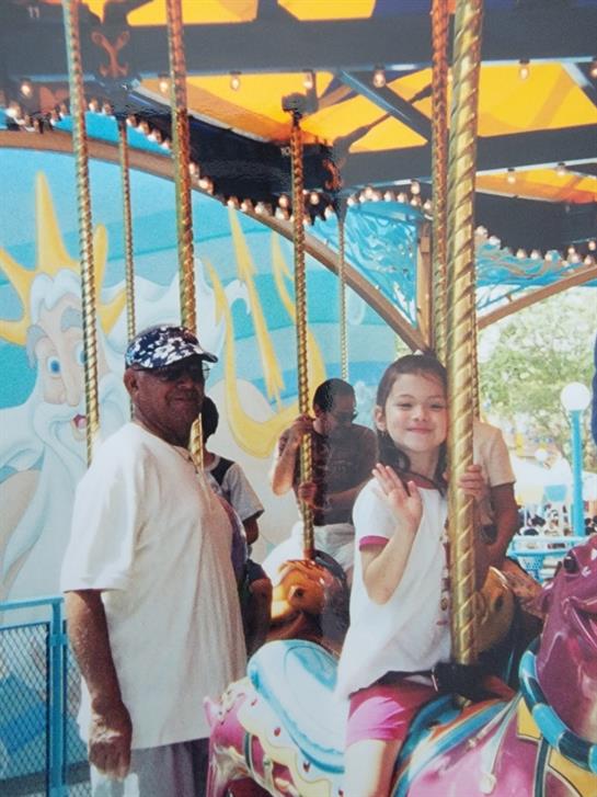 Kids are having fun on a carousel ride at a vibrant fairground during a sunny day.