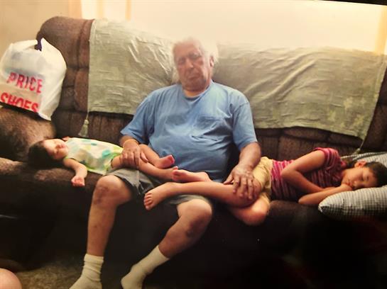Children relax on a couch with an elderly man, creating a warm, cozy atmosphere.