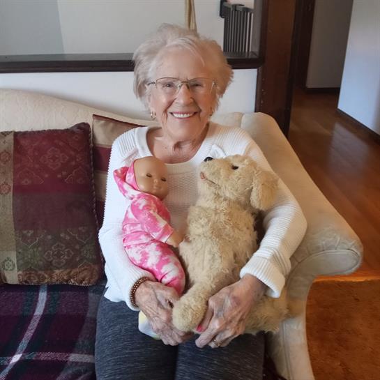 A woman holding a doll and a stuffed animal