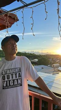 A man stands on a rooftop in Vigan, gazing at the sunset, creating a serene atmosphere.