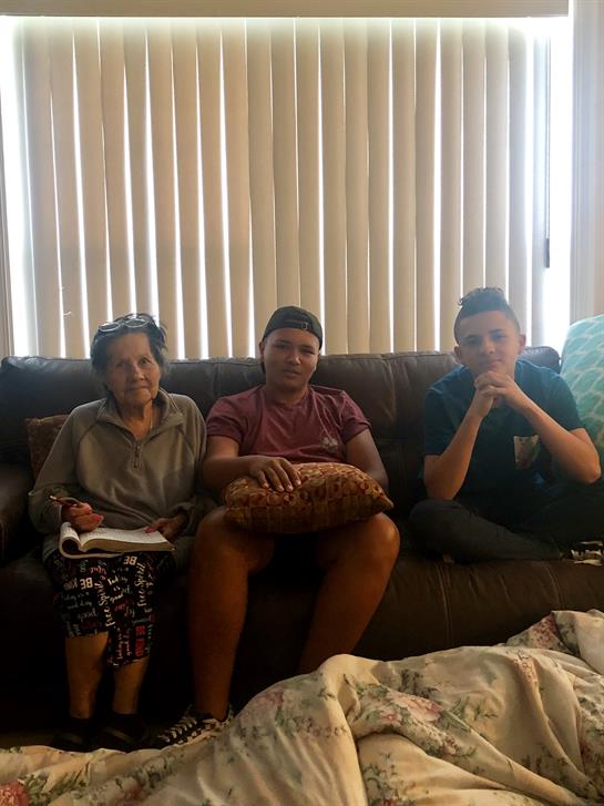Three relatives sit comfortably on a couch in a cozy living room, enjoying each other's company.