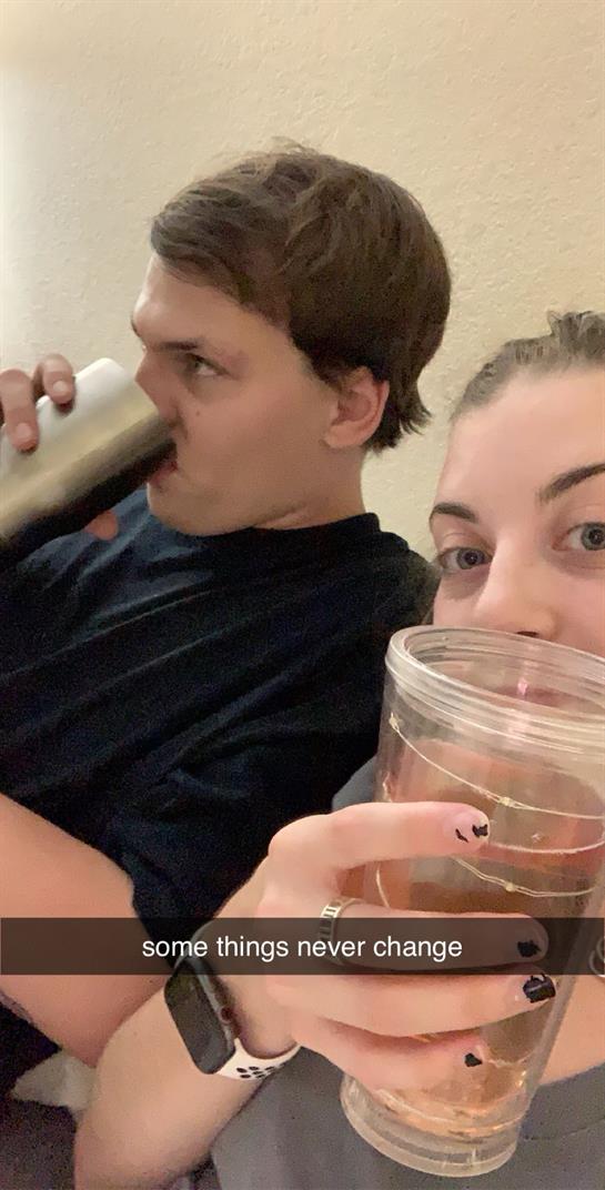 Two friends sit close, sipping their beverages and enjoying each other's company at home.