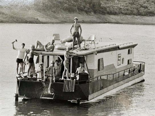 Friends gather on a boat to spend a sunny day at the lake, relaxing and having fun together.