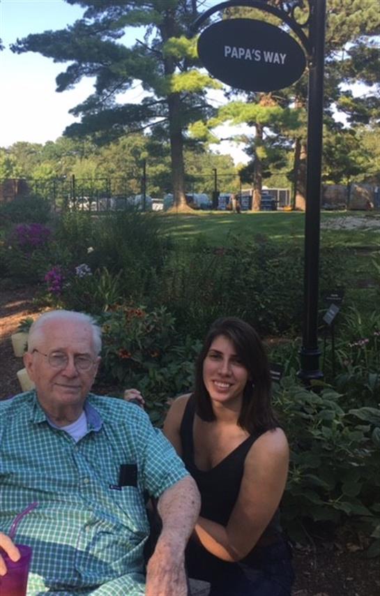 A young woman and an elderly man enjoy quality time together in a vibrant garden.