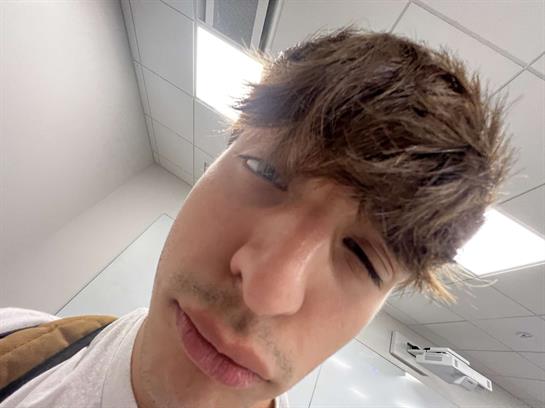 A man is making a humorous face with his hair unkempt in a well-lit indoor space.