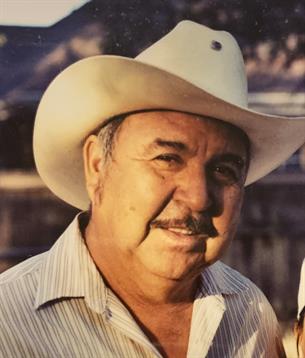 A man with a friendly expression wears a cowboy hat while standing outdoors.