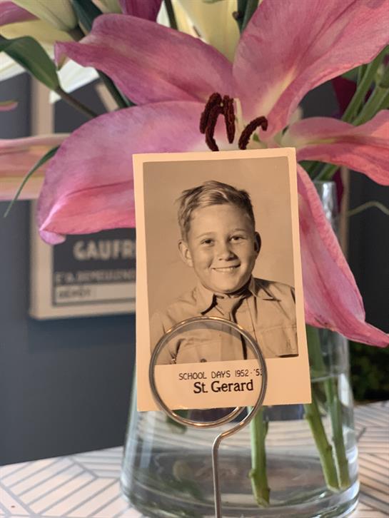 A charming school photograph of a young boy is placed in a vase amid pink lilies.