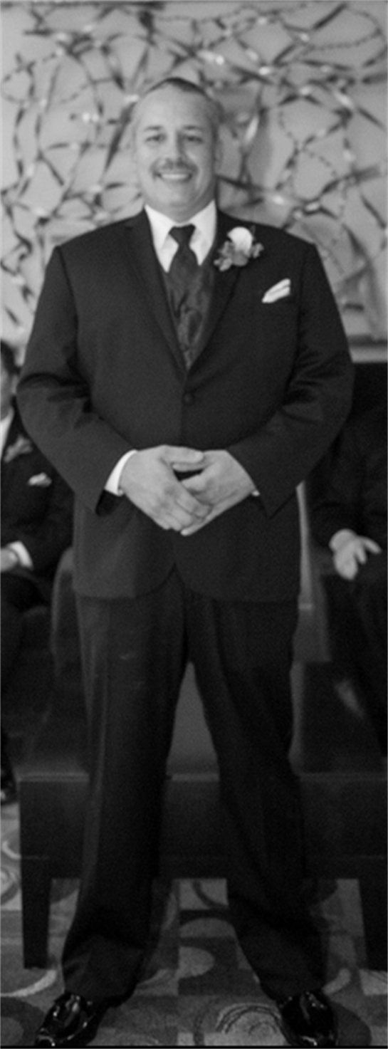 A groom stands proudly in a formal suit at a wedding reception, exuding joy and anticipation.