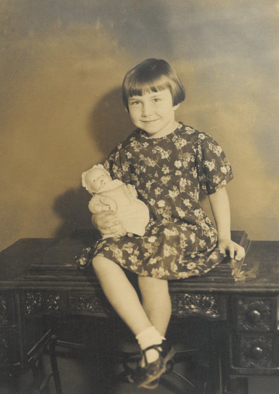 A girl sitting on a table holding a doll