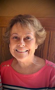 A cheerful senior woman with short hair enjoys a moment of happiness at a table.