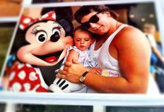 A mother holds her child close while posing with a cheerful character in a bright atmosphere.