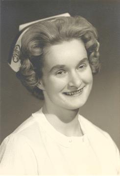 A young woman in a nursing uniform smiles gently, showcasing her pride in her profession.