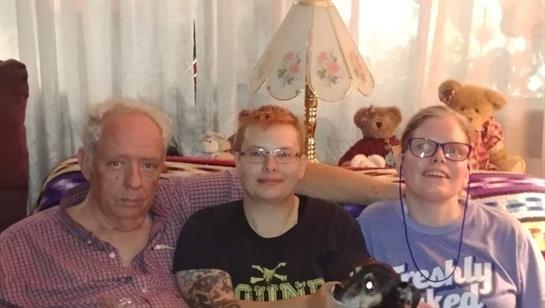 Three individuals relax together with a small dog in a warm, inviting living space.