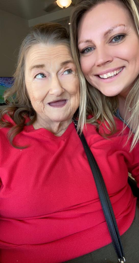 Two women share a warm smile in a comfortable indoor environment, highlighting their bond.