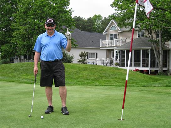 Golfer on the green celebrates a good shot with a raised finger.