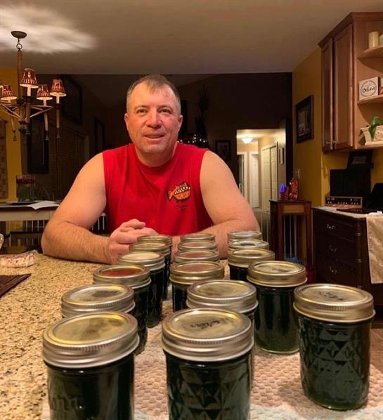 A man sitting at a table with jars of jam
