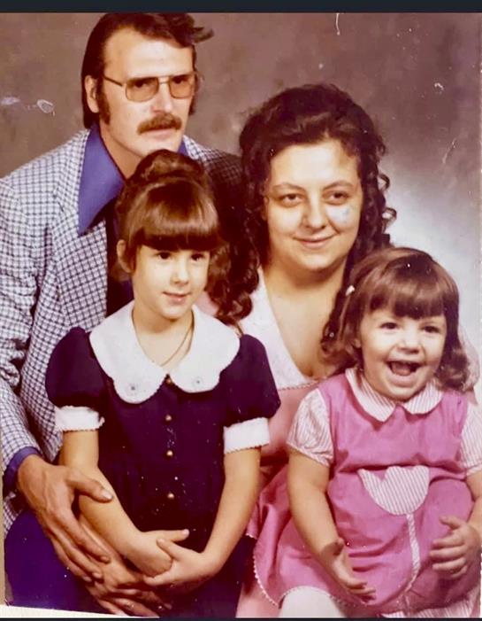A family poses together in a vintage studio, capturing a joyful moment with smiles.