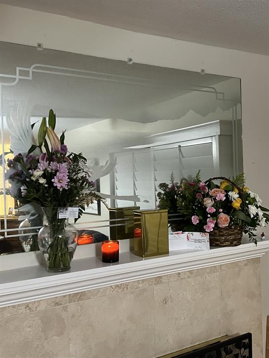 A warm living room showcases vibrant flowers and soft candlelight on the mantle.