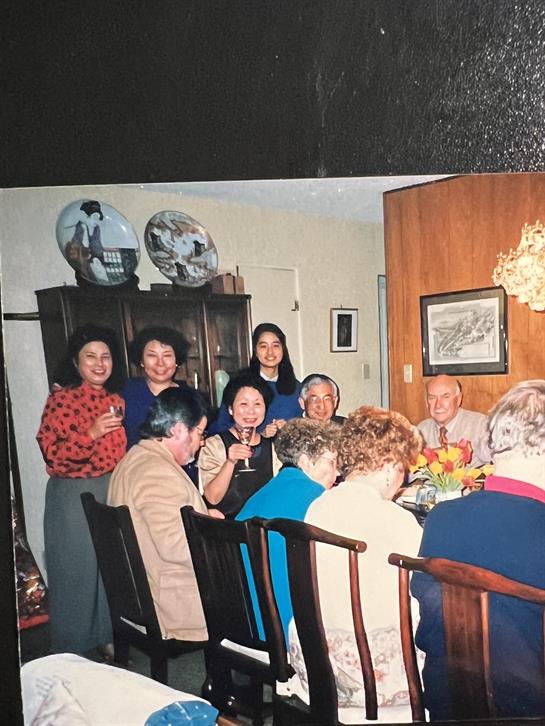 Friends and family gather around a dinner table, sharing a joyful meal and conversation together.